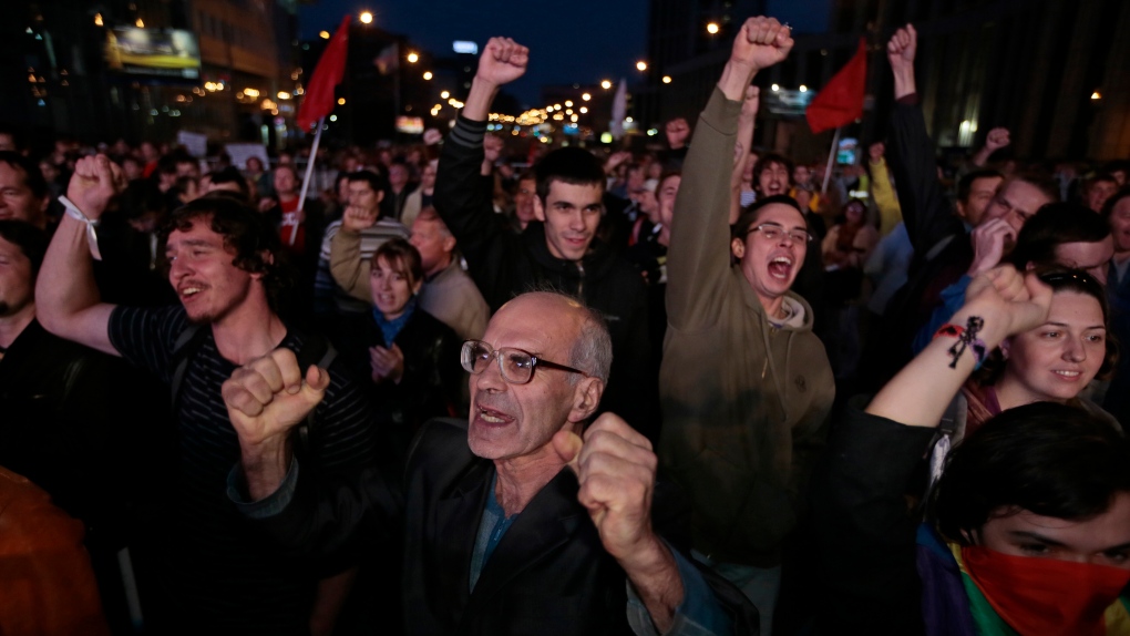 Opposition protesters react while listening to an orator during a protest rally in Moscow