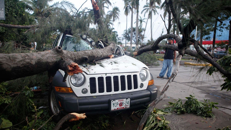 A man stands next to a vehicle damaged by a fallen tree due to the passage of Hurricane Karl in Veracruz, Mexico, Friday, Sept. 17, 2010.  (AP / Alexandre Meneghini)
