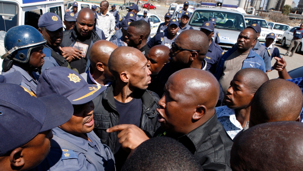 Firebrand politician Julius Malema, right argues with police officers, at Lonmin Platinum Mine