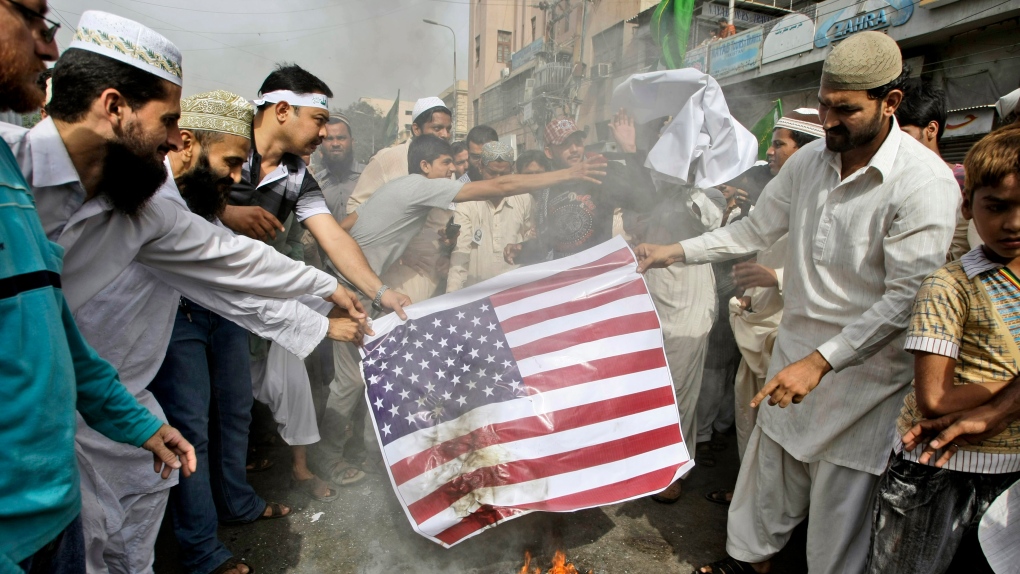 Pakistani supporters of Jamaat-e-Ahle-e-Sunnat burn a representation of a U.S. flag during a demonst