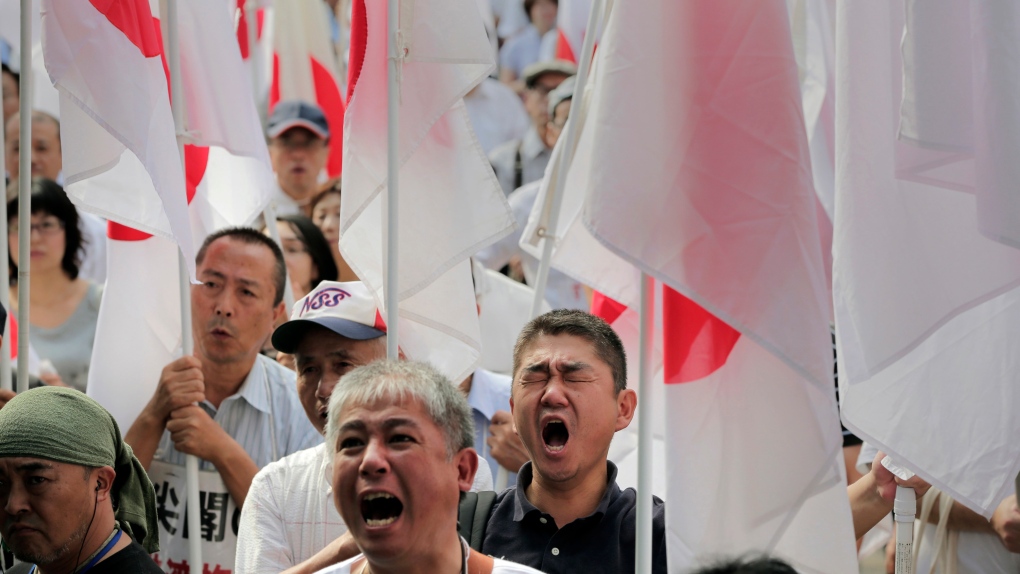 Protesters holding Japanese national flags shout slogans during a rally