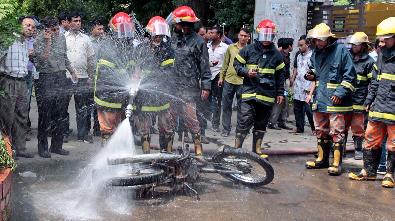 Bangladeshi firefighters douse a motorbike after it was set on fire in Dhaka on Sept. 22, 2012.