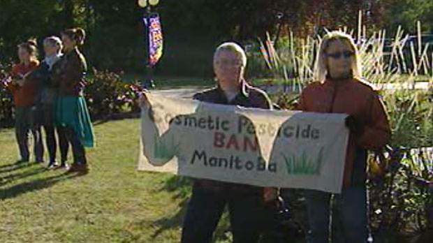 A group holds a sign to protest the use of cosmetic pesticides in Manitoba.