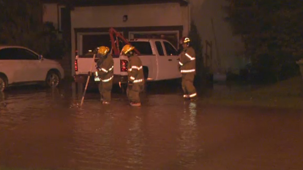Firefighters examine a flooded driveway in Brossard