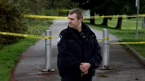 A police officer stands at the entrance to a pathway as other officers investigate the beating death of a 15-year-old girl at Mackie Park in Delta, B.C., on Sunday September 26, 2010. (CP/Darryl Dyck)