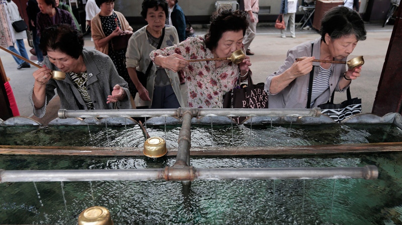 In this Saturday, Sept. 29, 2012 photo, elderly women rinse their mouths with holy water at a shrine