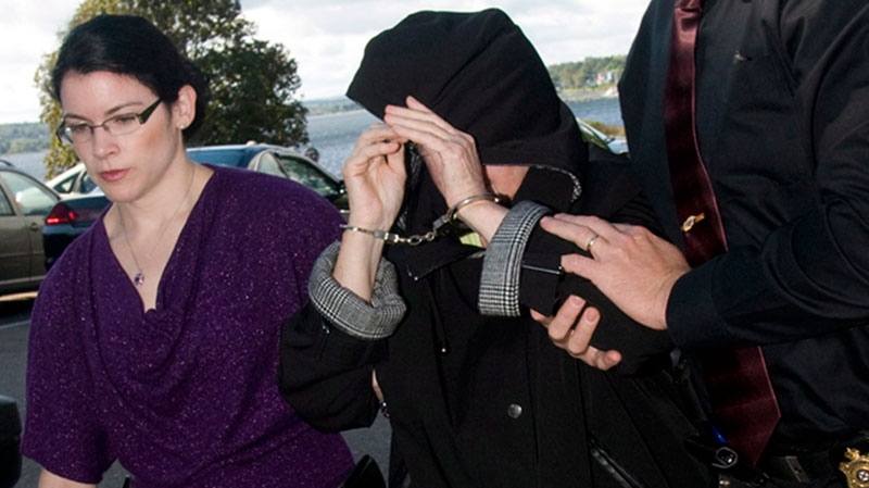 Melissa Ann Weeks, 77, of New Glasgow, N.S., also known as the 'Internet Black Widow,' leaves a Cape Breton Regional Police Services vehicle escorted by Const. Erin Donovan, left, and Const.Geoff MacLeod for a court appearance at the Sydney Justice Centre Tuesday, Oct. 2, 2012. (Vaughan Merchant / THE CANADIAN PRESS)