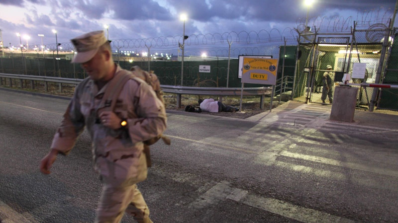 In this May 13, 2009, file photo, reviewed by the U.S. military, a U.S. trooper walks near an entrance to the Guantanamo detention facility at dawn, at Guantanamo Bay U.S. Naval Base, Cuba. (AP Photo/Brennan Linsley)