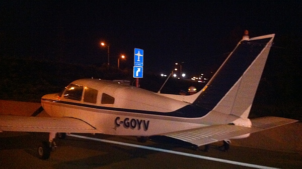 This Piper aircraft made a safe landing on Highway 407 near Woodbine Ave. late on Friday, Oct. 8, 2010. Note the sign pointing to nearby Buttonville Airport. (Tom Podolec/CTV Toronto)