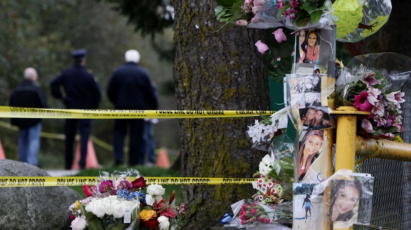 Police officers continue to investigate as flowers and photographs sit at a memorial for 15-year-old Laura Szendrei in Delta, B.C., on Friday October 8, 2010. (Darryl Dyck / THE CANADIAN PRESS)