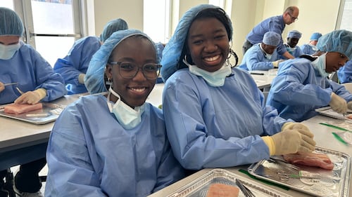 Students wear blue scrubs in a classroom.
