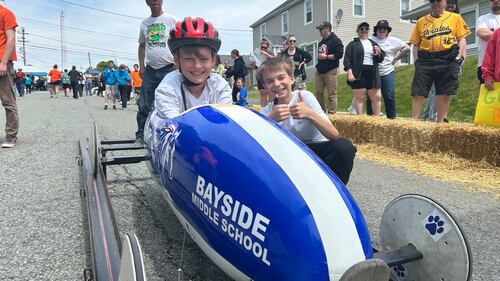A soap box derby driver is pictured in a blue car.