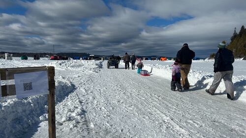 Anglers are pictured walking along a snowy road beside an ATV on their way to the frozen lake and fishing tents at Dominion Park in Saint John, N.B. (Avery MacRae / CTV Atlantic)
