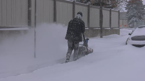 A person clears snow from a sidewalk on Feb. 17, 2026. (Miriam Valdes-Carletti / CTV News Edmonton)