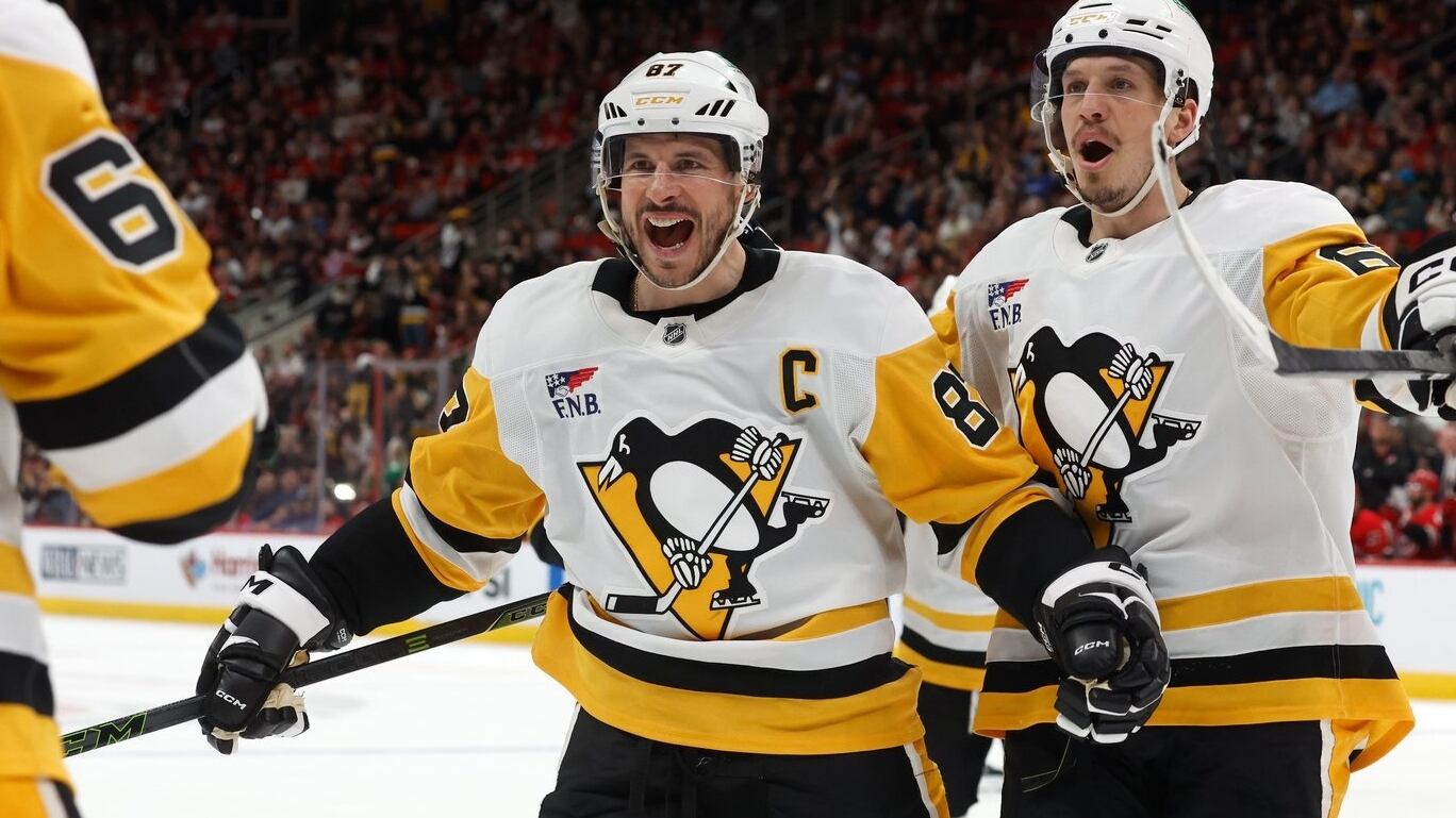 Pittsburgh Penguins' Sidney Crosby (87) comes to congratulate teammate Erik Karlsson, left, on his goal with Rickard Rakell, right, during the third period of an NHL hockey game against the Carolina Hurricanes in Raleigh, N.C., Wednesday, March 18, 2026. (AP Photo/Karl DeBlaker)