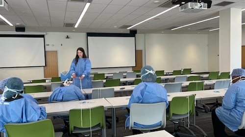 Students wear blue scrubs in a classroom.