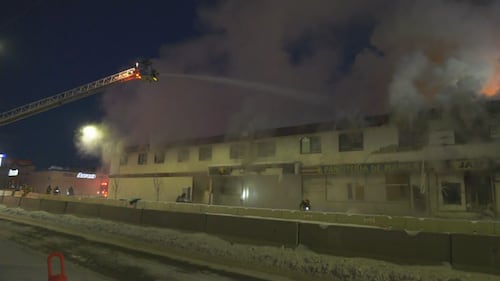 Firefighters on ladder trucks spray water on a fire at the former Jasper Place Hotel along Stony Plain Road in Edmonton the early morning of Feb. 19, 2026. (Sean McClune / CTV News Edmonton)