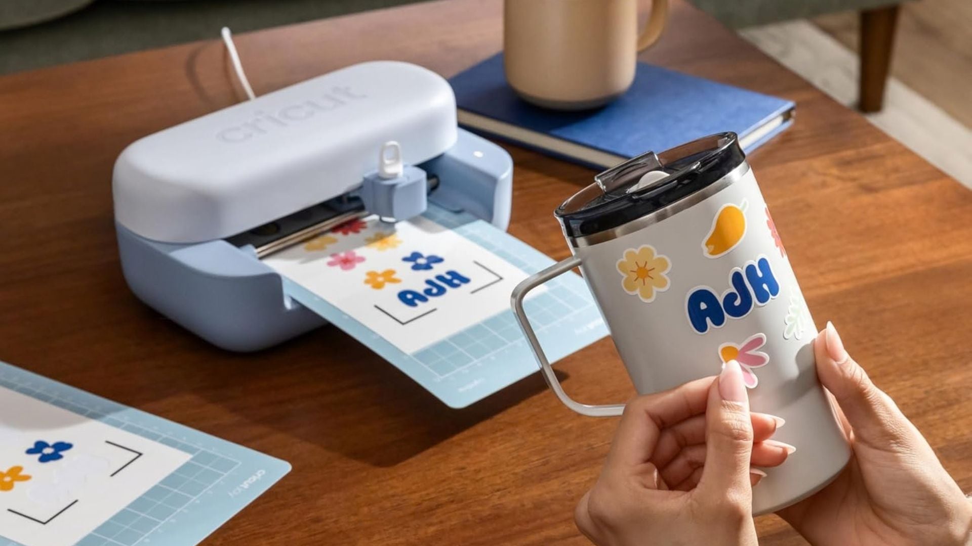 A person using a Cricut crafting machine to decorate a personalized travel tumbler.