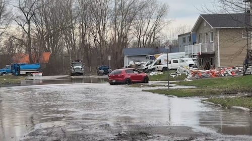 A car drives down a flooded street.