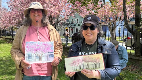 Two artists pose with their paintings of cherry blossoms.
