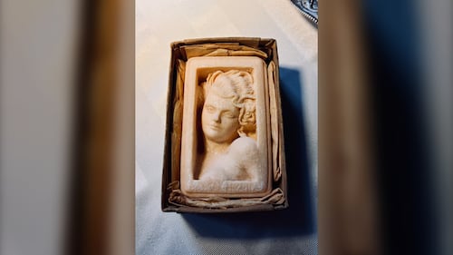 An antique figurine of a woman is pictured.