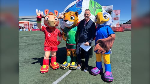 A man poses with three mascots.