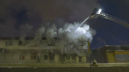 Firefighters on ladder trucks spray water on a fire at the former Jasper Place Hotel along Stony Plain Road in Edmonton the early morning of Feb. 19, 2026. (Sean McClune / CTV News Edmonton)