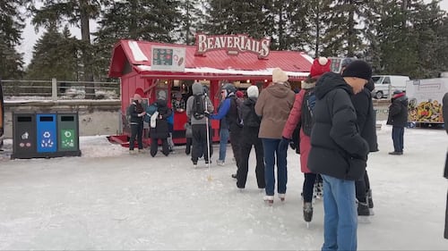 skaters line up in front of a red beavertails stand on ice