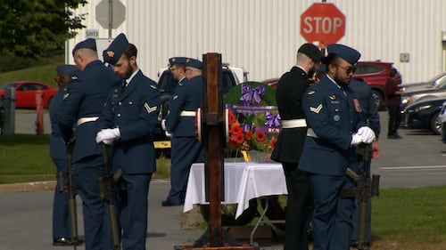 Members of the military stand with their heads bowed.