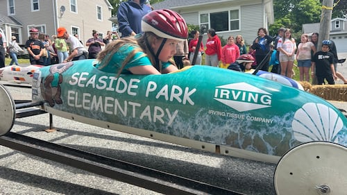 A soap box derby driver is pictured in a teal car.