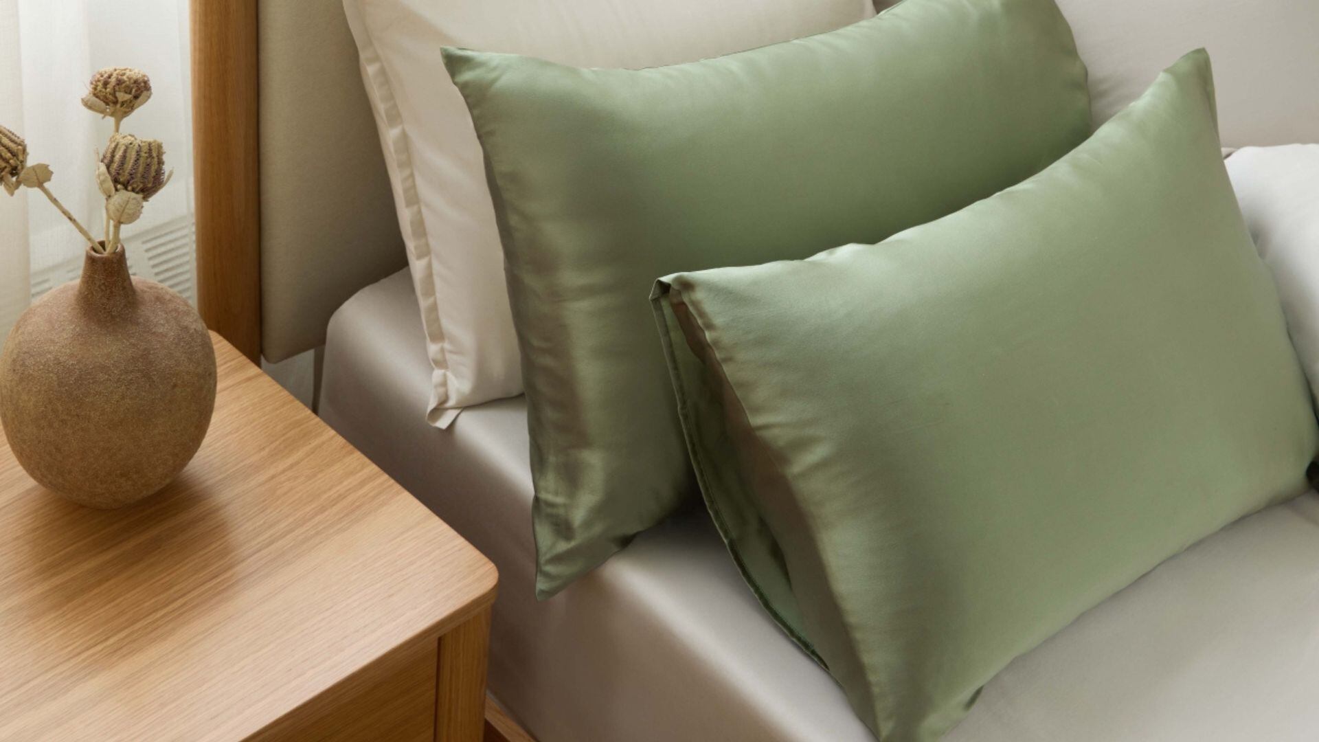 Two silk pillowcases on a bed with other Silk & Snow bedding.