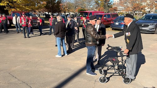 Veterans shake hands in a parking lot.