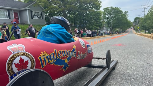 A soap box derby racer is pictured in a red car.