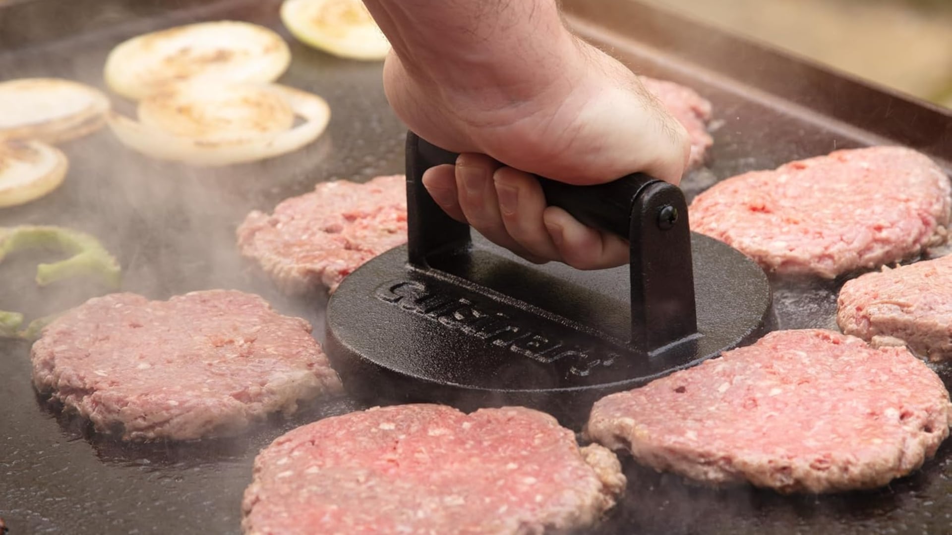 A person using a Cuisinart press to smash a burger.