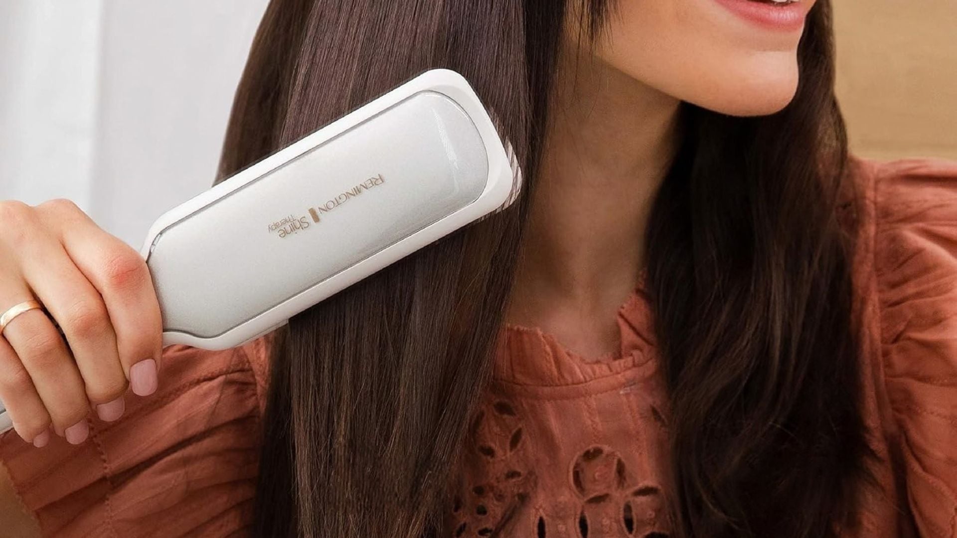 A person straightening their hair with a Remington straightener.