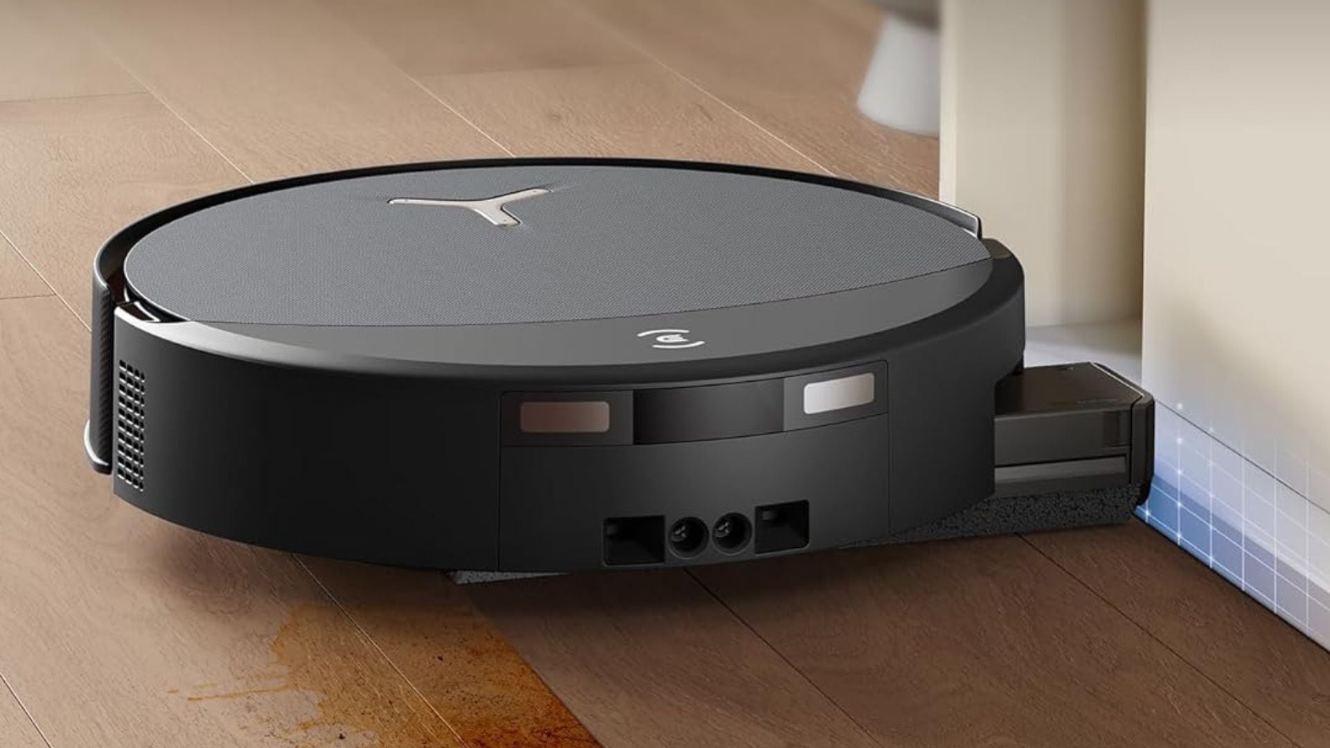 A black Ecovacs Robot Mop is cleaning a baseboard.