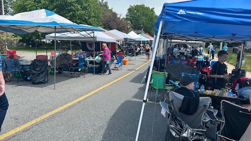 Outdoor event tents are pictured with people underneath.