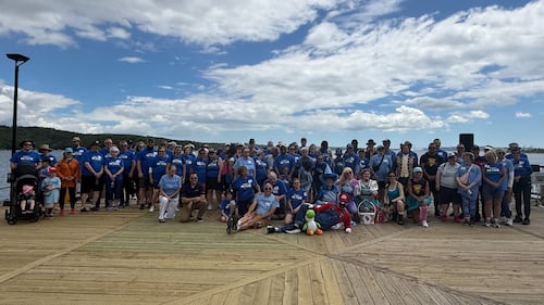 A large group of people pose for a photo on a boardwalk.