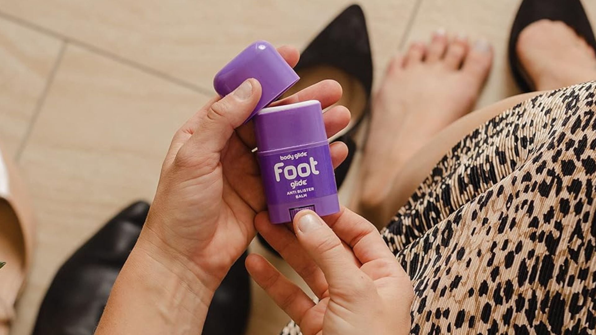 A person taking the lid off of Body Glide Foot Glide.