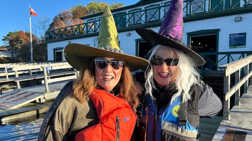 Two women pose for a photo while dressed up as witches.