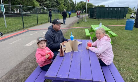 A family sits at a purple picnic table.
