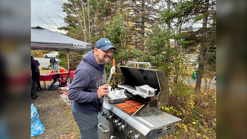 A man is pictured cooking hot dogs on a barbecue and pretending to take a bite at the Gaetz Brook Greenway during the Halloween Trick-or-Treat Trail Walk in East Chezzetcook, N.S., on October 25, 2025. (Emma Convey / CTV Atlantic)