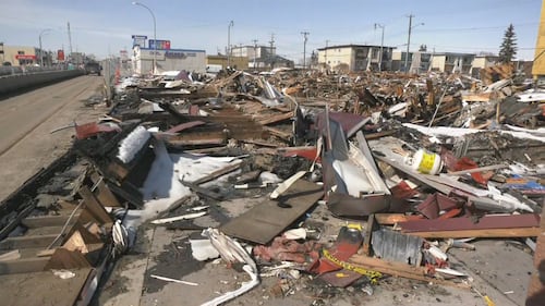 Piles of debris from a Feb. 19 fire at the Jasper Place Hotel sit inches from Stony Plain Road on April 1, 2026. (Galen McDougall/CTV News Edmonton)