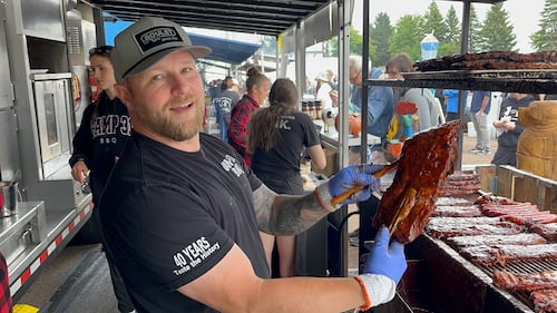 A man holds a rack of ribs.