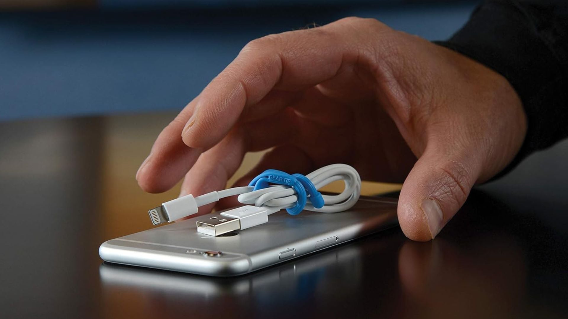 A Nite Ize Gear Tie wrapped around a charging cord, sitting on top of a phone.