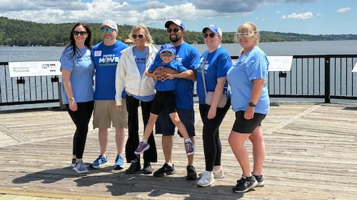 A group of people pose for a photo on a boardwalk.