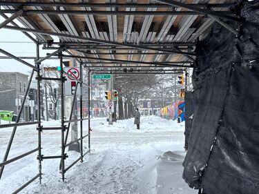 A man in a heavy trenchcoat coat and respiratory mask waits to cross the street in Halifax at the intersection of Robie and Almon Street on Jan. 26, 2026. (CTV Atlantic / Jesse Thomas)