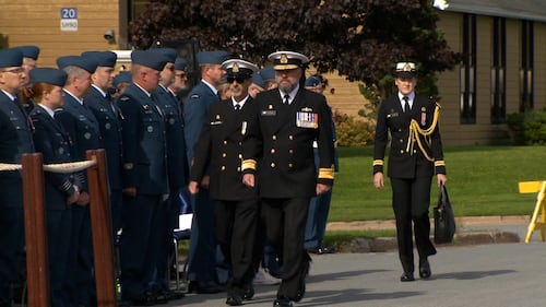 Members of the military march toward a podium.