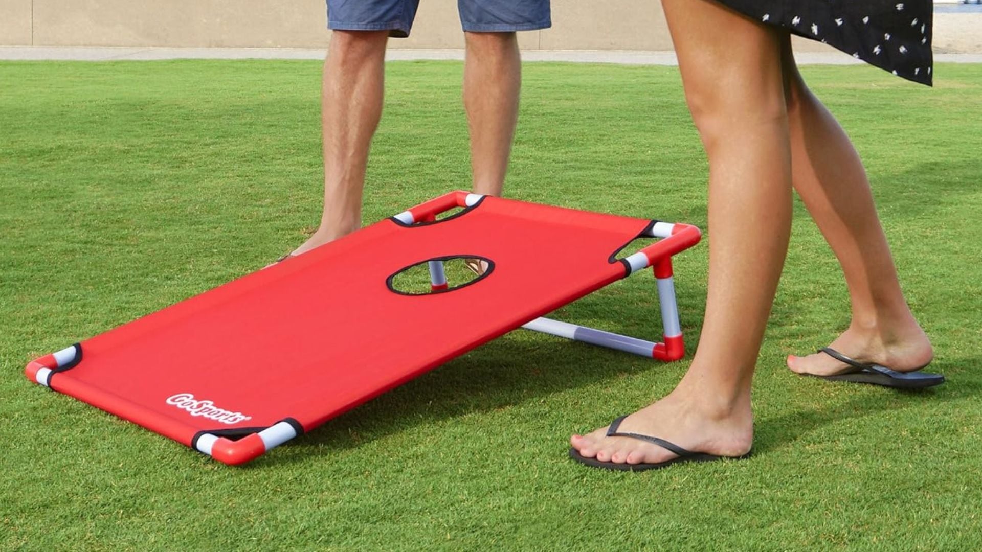 people standing next to a cornhole target on a lawn