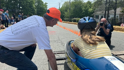 A man talks to a soap box derby driver.